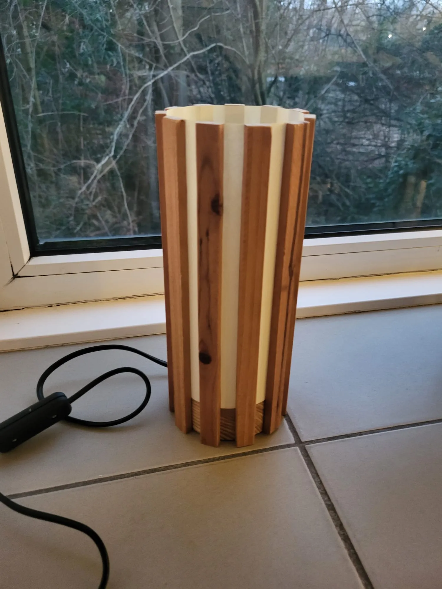 Verticale lamp met houten en witte latjes in een venster