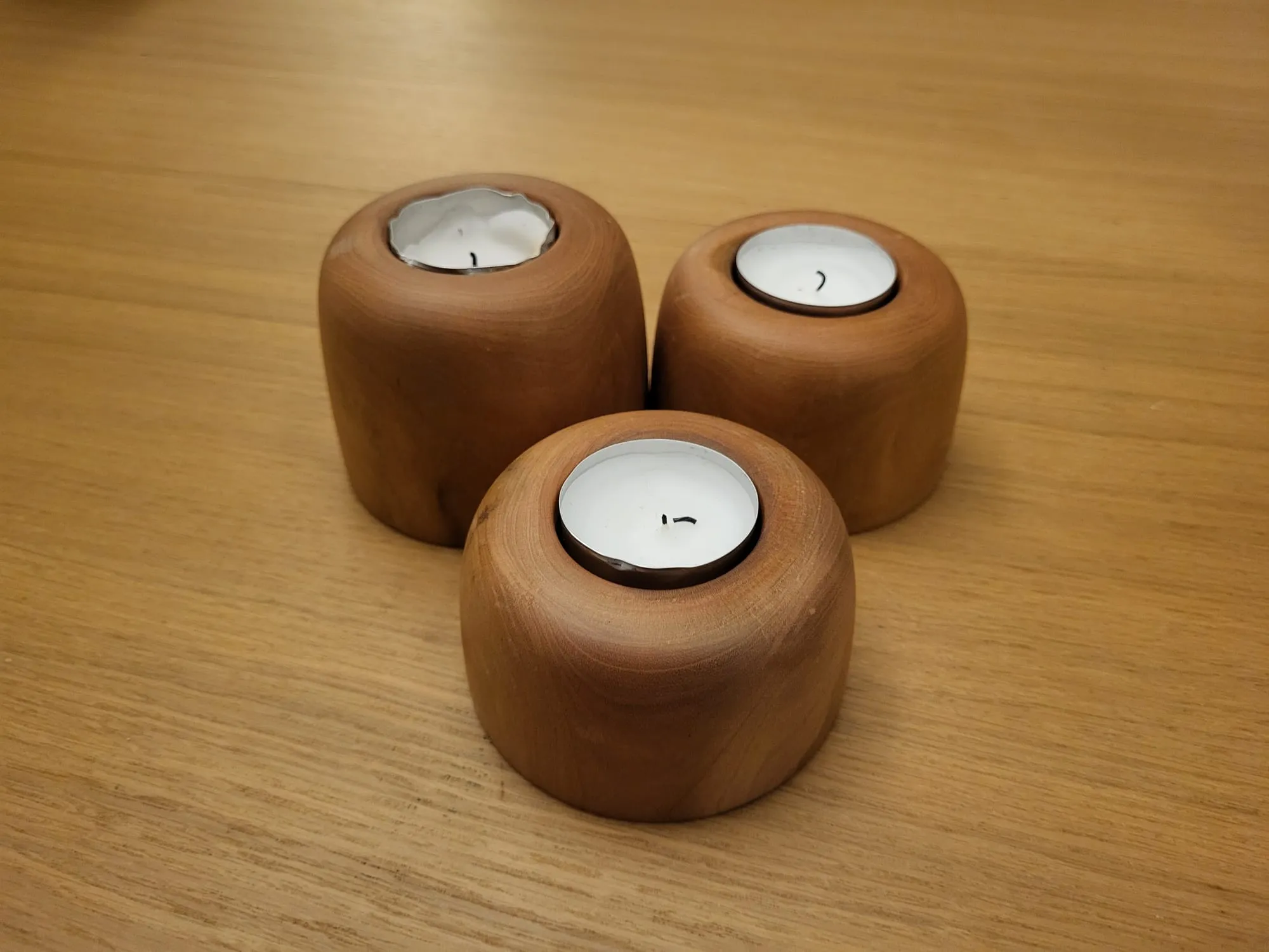 Drie houten waxinelichthouders op een tafelblad